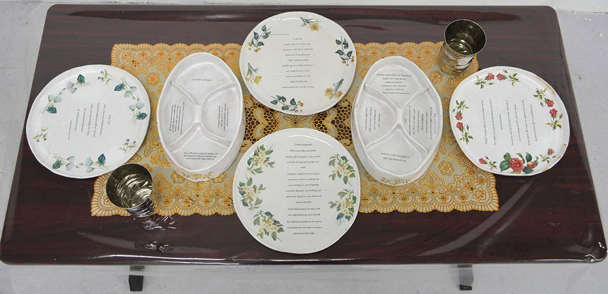 Ceramic plates displayed on gold doily and mahogany table.